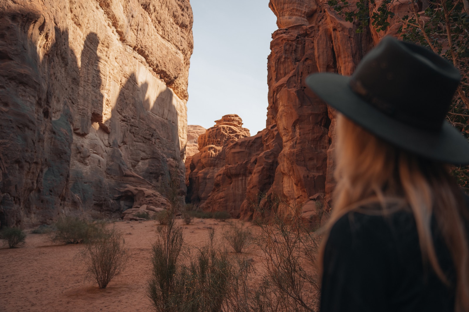 a woman wearing a hat standing in a canyon